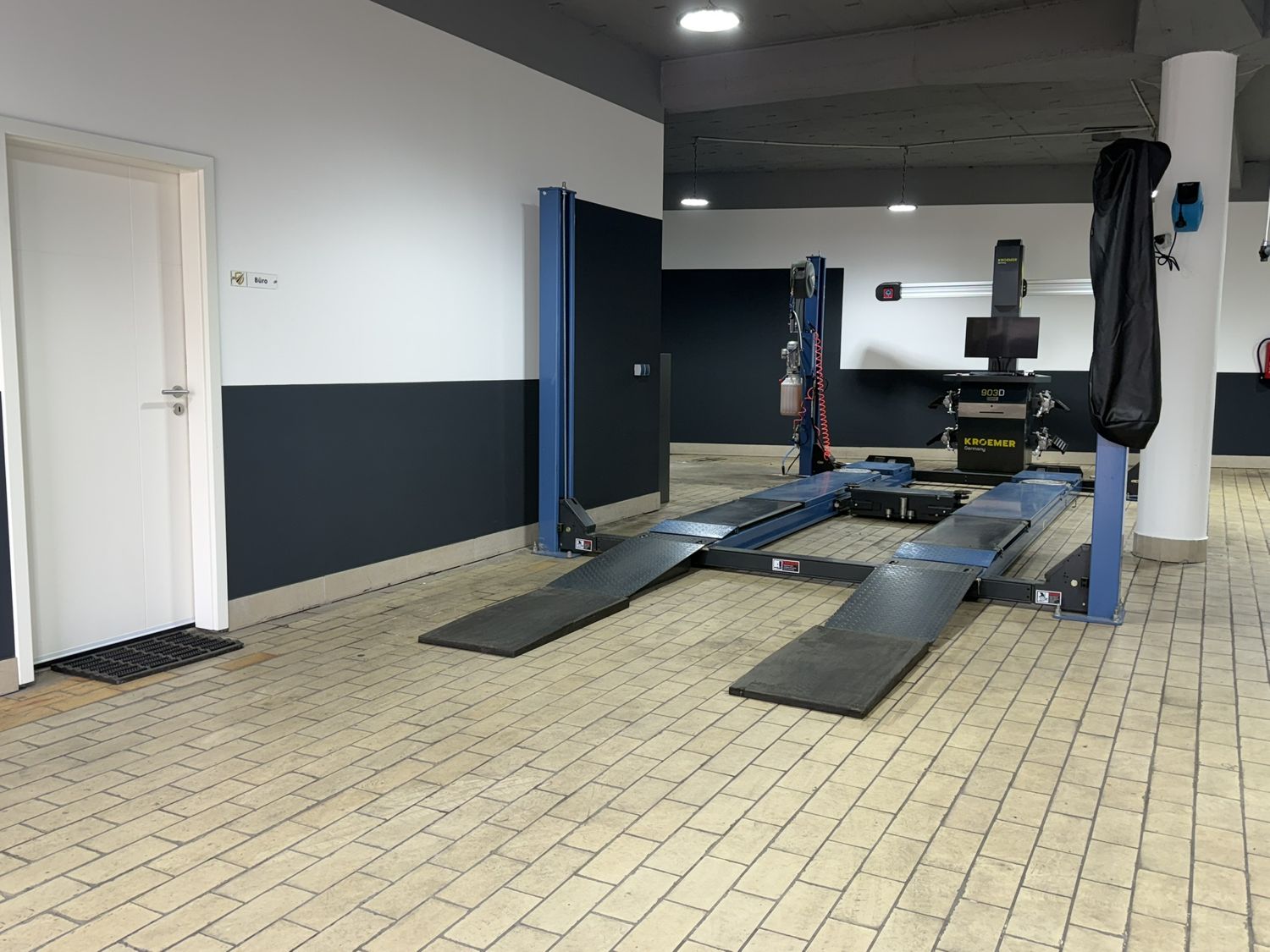 Zweite Ansicht der Halle mit Hebebühne, Achsmessgerät und Bürotür